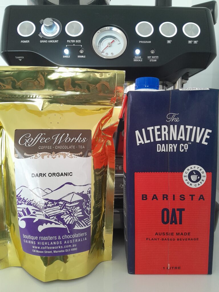 CoffeeWorks "Dark Organic" coffee beans and Alternative Dairy Co. oat milk, in front of Breville Barisa Express coffee machine