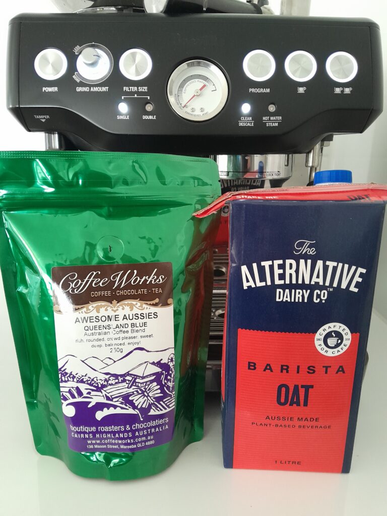 CoffeeWorks "Queensland Blue" coffee beans and Alternative Dairy Co. oat milk, in front of Breville Barisa Express coffee machine